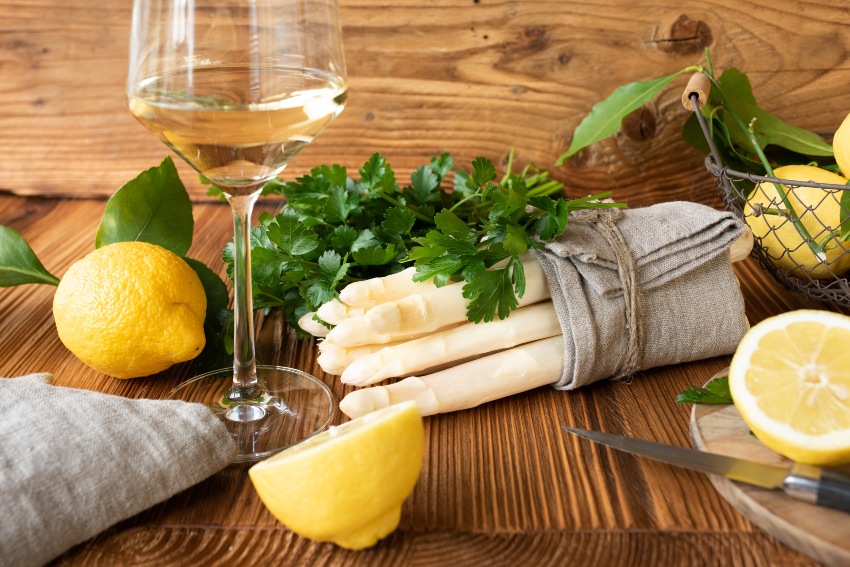 Frische Zutaten für ein Spargelessen auf rustikalem Holz. Konzepthintergrund für Küche und Gastronomie.
