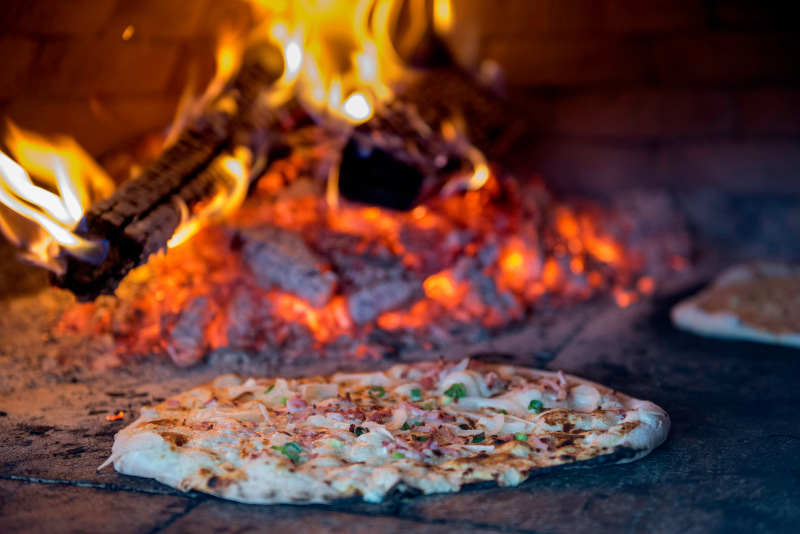 Ein Flammkuchen wird im holzbefeuerten Ofen gebacken