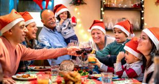 Familie am großen Tisch stößt mit Wein auf das Essen an