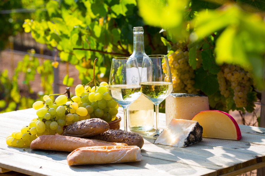 Wein, Baguette und Käse auf einem Tisch drapiert