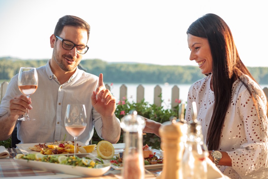Junges Paar sistz am Tisch, isst und trinkt Wein