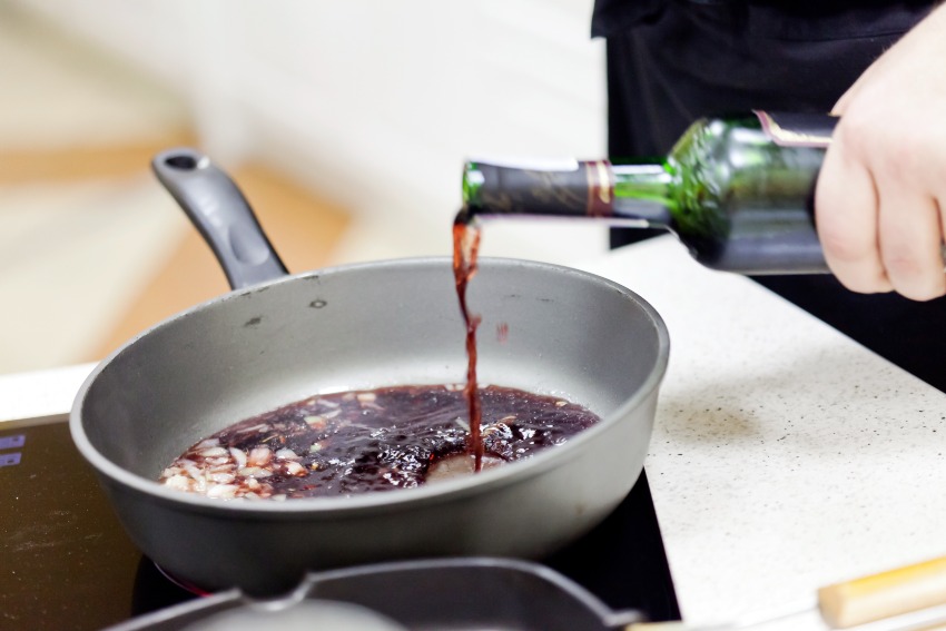 Rotwein wird in eine Pfanne gegeben - Wein zu Kaninchen