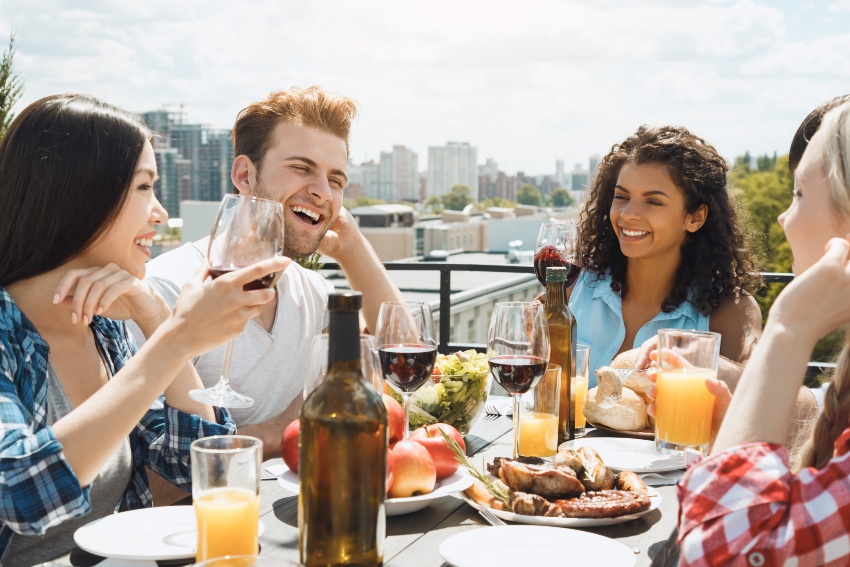 Gruppe junger Leute auf einem Balkon beim Grillen und Rotweintrinken - Welcher Wein zu Rinderfilet?