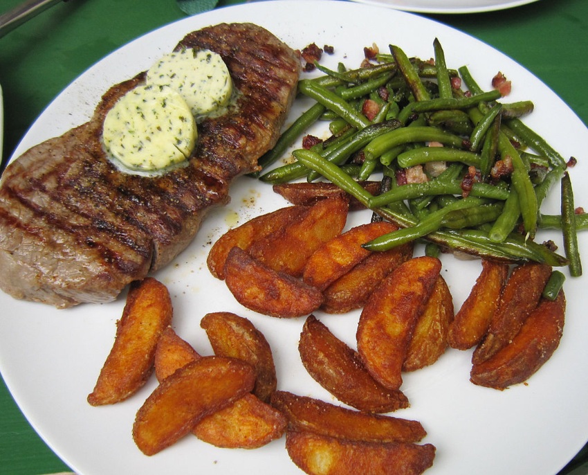 Rumpsteakgericht mit Kräuterbutter, Kartoffelecken und Speckbohnen